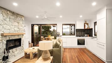 A modern kitchen with white cabinets, a stone wall, and a fireplace.