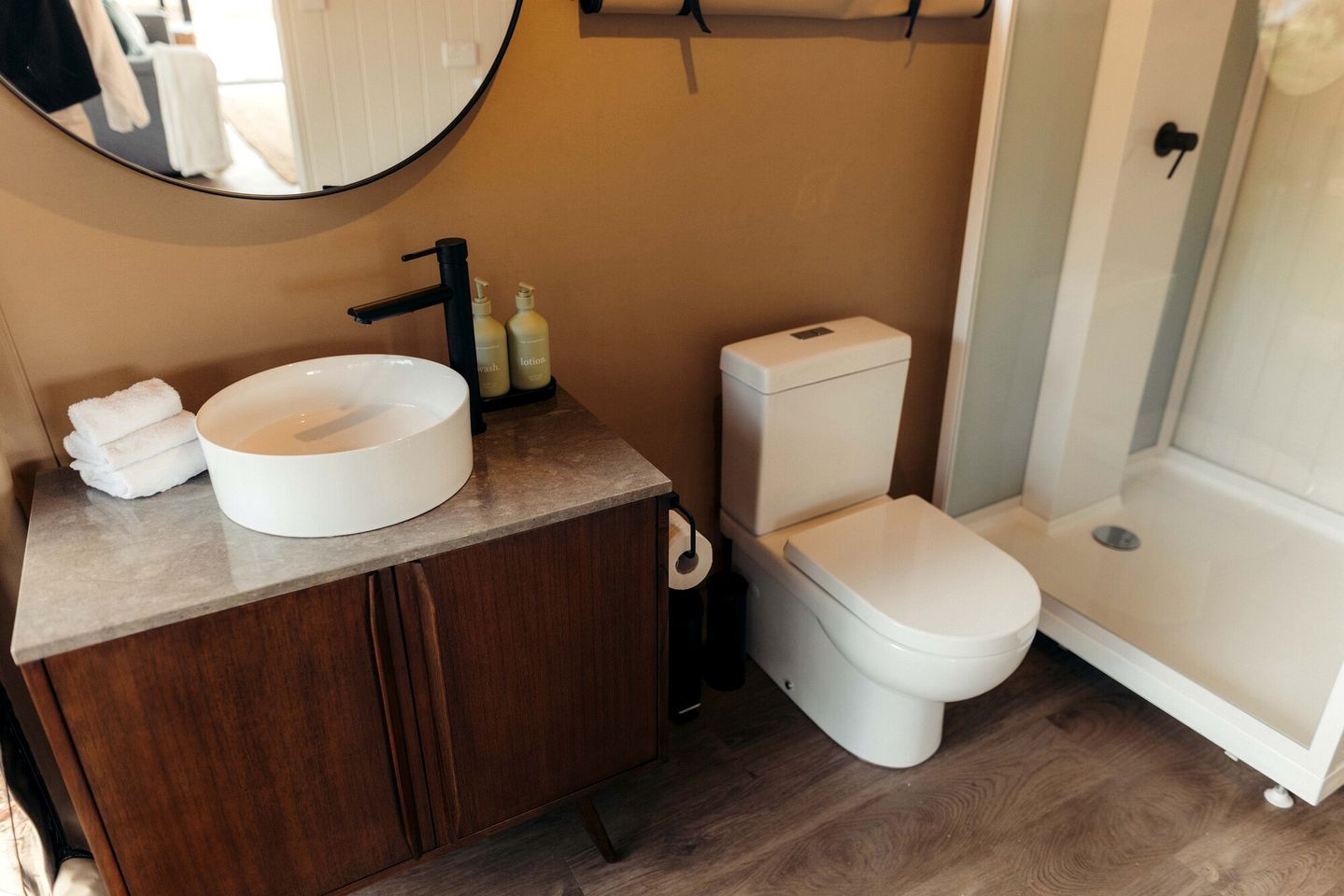 Une salle de bain avec un lavabo rond, des toilettes et une douche.