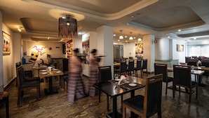 Ein Restaurantinneres mit Tischen, Stühlen und einer zentralen Dekoleuchte.