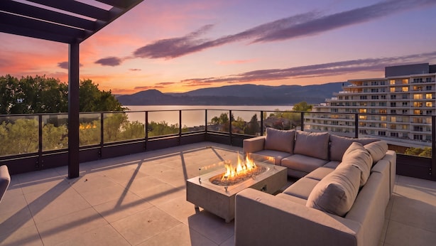 Eine Dachterrasse mit Feuerstelle, Lounge-Sofa und Blick auf die untergehende Stadt.