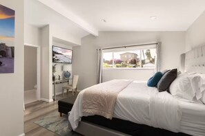 Um quarto com cama, escrivaninha e cadeira.