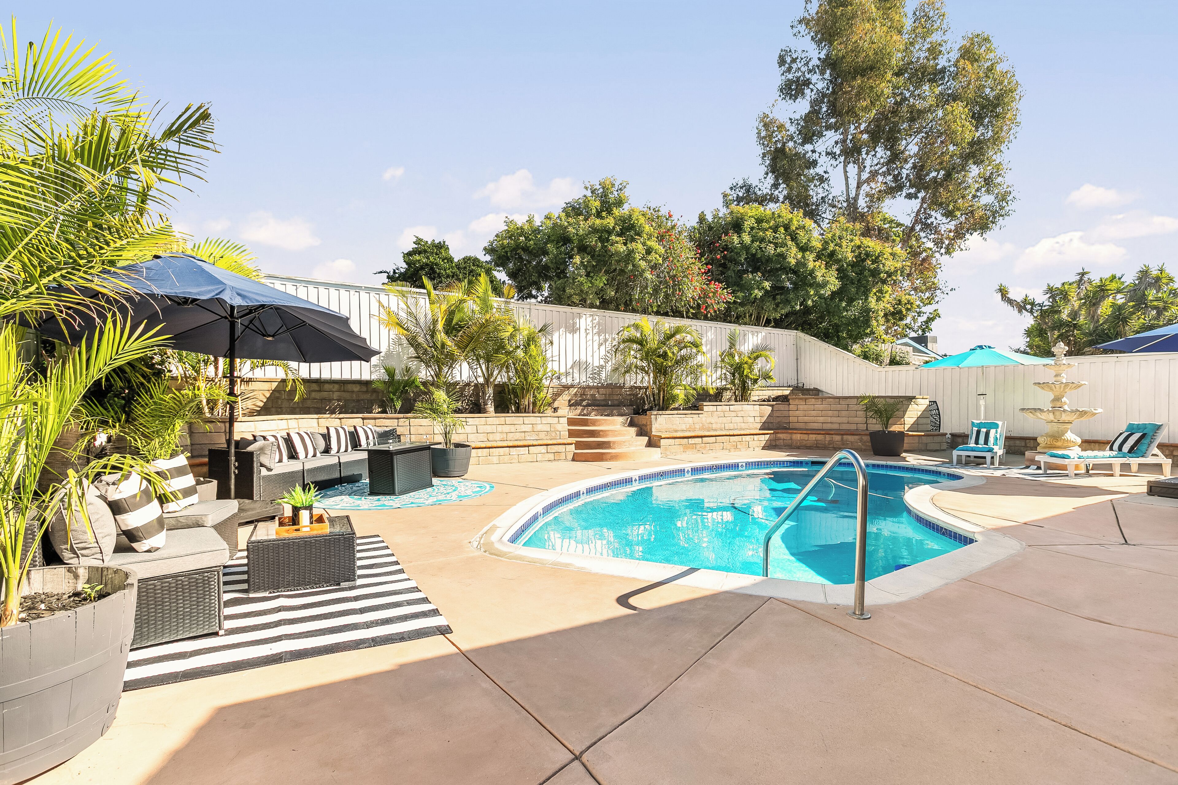 A swimming pool with a sunken seating area, surrounded by lounge chairs and umbrellas.