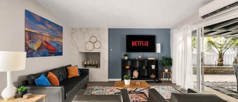 A modern living room with a sofa, coffee table, and a TV displaying 'NETFLIX'.