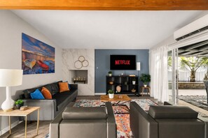 Een moderne woonkamer met een bank, salontafel en een televisie waarop 'NETFLIX' wordt getoond.