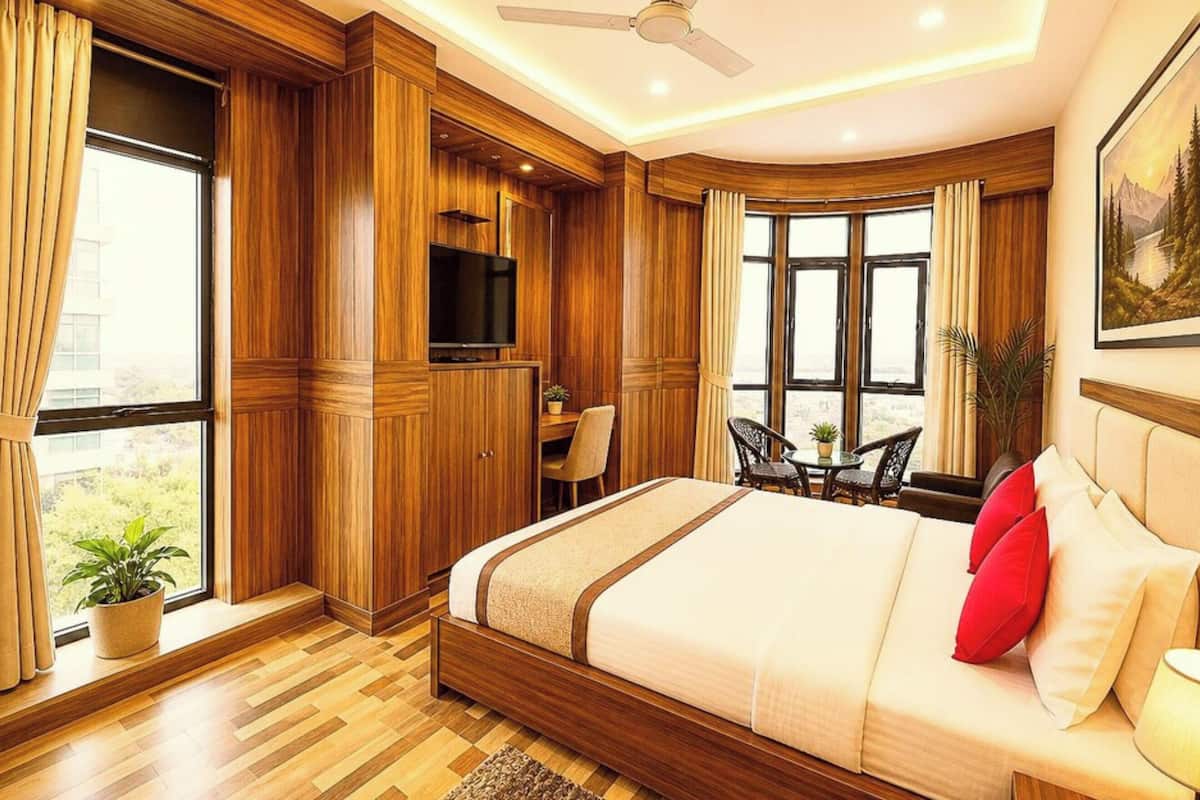 A bedroom with a bed, a TV, a desk, and a balcony.