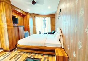 Un dormitorio con una cama grande, paredes de madera, una televisión y una ventana con cortinas.