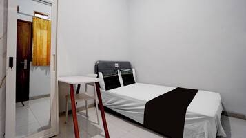 Um quarto pequeno e limpo com uma cama, uma escrivaninha e uma cadeira.