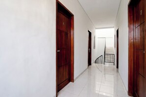Un couloir avec des portes en bois et un escalier menant à l’étage supérieur.