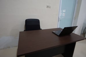 A wooden desk with a laptop, a black office chair, and a glass door.