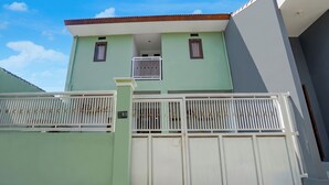 A two-story building with a gated entrance and a balcony. - OYO 95293 Citra Homestay Syariah (Pasuruan)