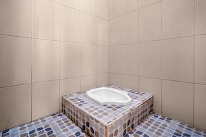 Une petite salle de bain carrelée avec des toilettes blanches.
