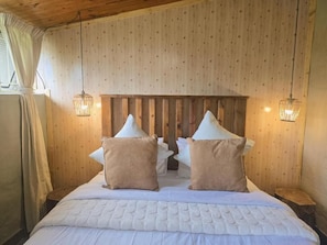 A bedroom with a wooden headboard, two bedside lamps, and a bed with a quilted cover.