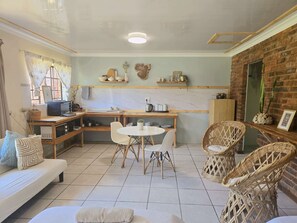 A cozy kitchen with a dining area, a sofa, and wicker chairs.
