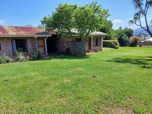 A brick house with a covered porch, a lawn, and a tree.