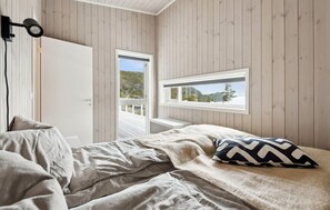 Ein Schlafzimmer mit Bett, einem Fenster mit Blick auf einen Wald und einer an der Wand befestigten Kamera.