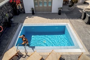 A swimming pool with a stone wall and potted plants. - Villa of your dreams in Akrotiri Santorini (Akrotiri)