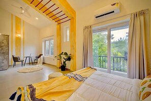 Ein Schlafzimmer mit Bett, Balkon, Essbereich und Blick auf Grünflächen.