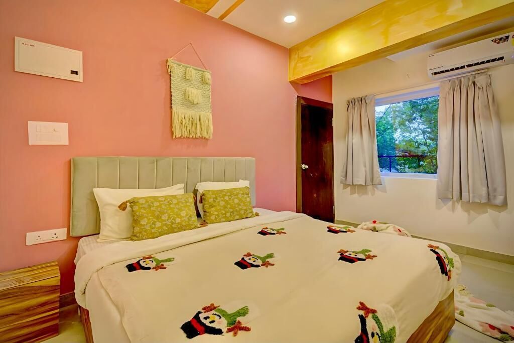 Quarto com cama, mesa de cabeceira, ar condicionado fixado na parede e janela com cortinas.