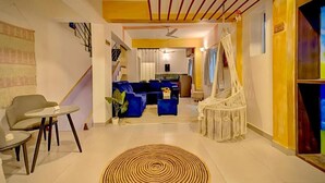 Una sala de estar moderna con un sofá, sillas, una mesa de centro, un sillón colgante de macramé y una escalera que lleva a otra habitación.