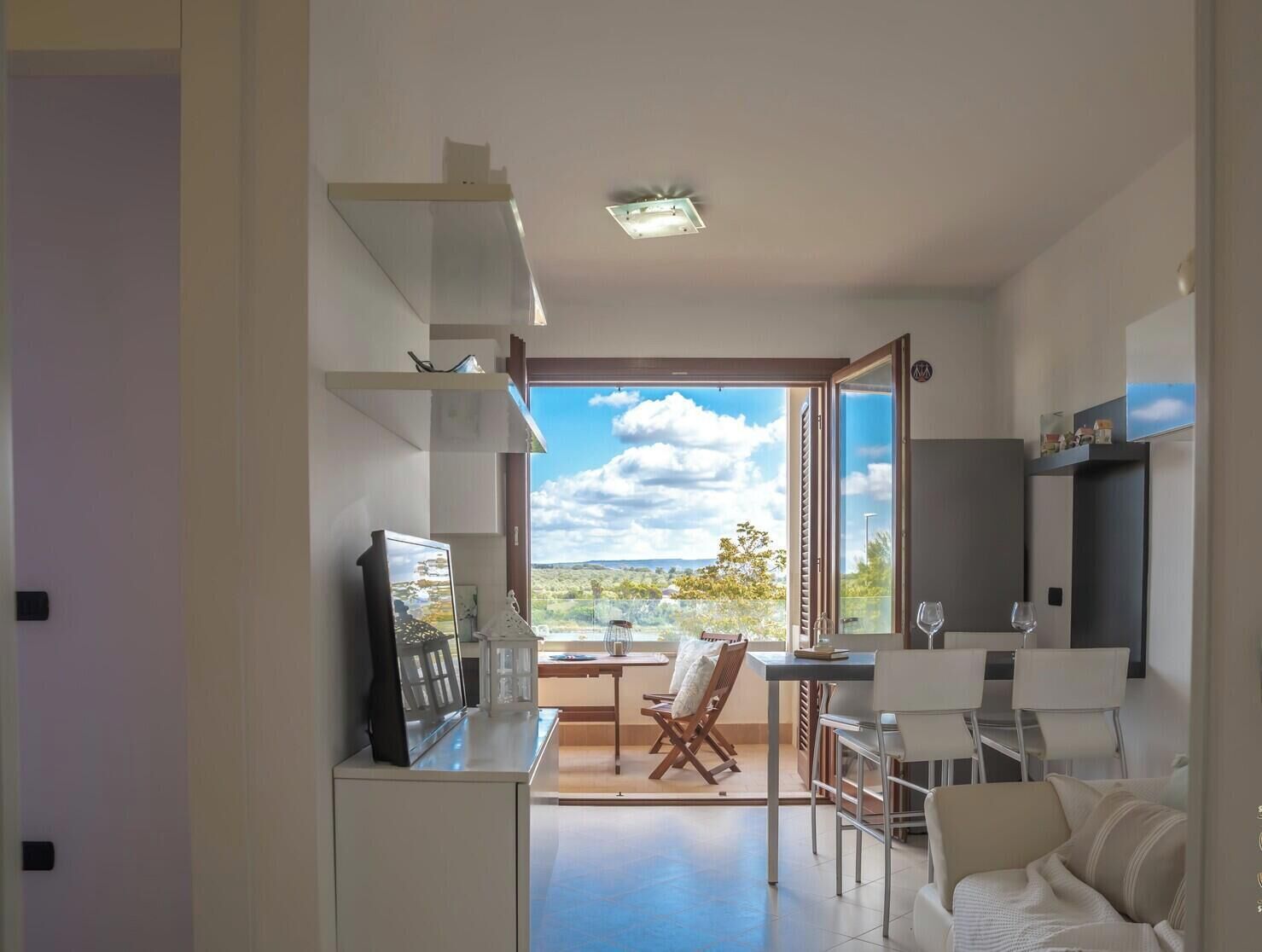 Ein modernes Wohnzimmer mit großem Fenster, Essbereich und Küche.