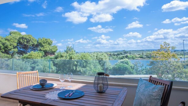 Un balcon avec une table dressée pour deux personnes, une vue dégagée sur le paysage et une lanterne en métal.