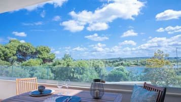 Ein Balkon mit Tisch für zwei Personen, freier Aussicht auf die Landschaft und einer Metalllaterne.