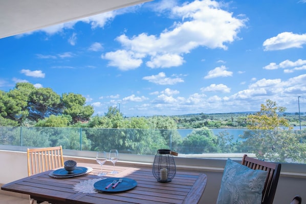 Ein Balkon mit Tisch für zwei Personen, freier Aussicht auf die Landschaft und einer Metalllaterne.