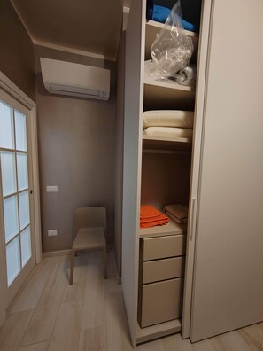 Ein begehbarer Kleiderschrank mit einer Bank, einem Bett und einem Heizgerät.