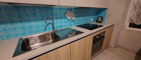 A kitchen with a sink, a kettle, and a window.