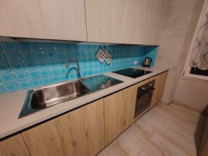Eine Küche mit Spüle, Wasserkocher und Fenster.