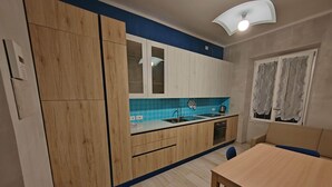 A kitchen with wooden cabinets, a blue backsplash, a sink, a stove, and a dining area with a table and chairs. - Gozzi's Den - Alghero (Alghero)