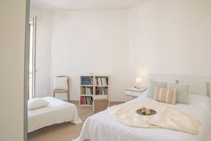 A bedroom with a bed, bedside tables, a bookshelf, and a chair. - Infinite Blue View-Alghero (Alghero)