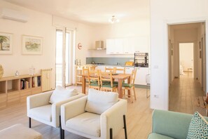 A modern apartment with a dining area, kitchenette, and a living room with two sofas. - Infinite Blue View-Alghero (Alghero)