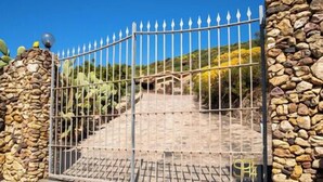 Ein verschlossenes Tor mit einem Metallzaun, Steinmauern und einer Treppe, die zu einer höheren Ebene führt.