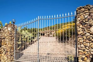 Ein verschlossenes Tor mit einem Metallzaun, Steinmauern und einer Treppe, die zu einer höheren Ebene führt.