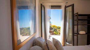Ein Schlafzimmer mit einem Bett, einem Fenster und Blick auf einen Garten.