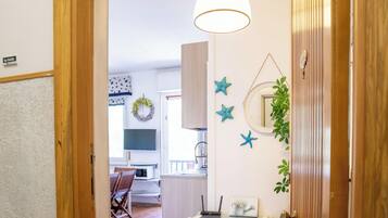 Un corridoio con una porta in legno, una parete bianca e vista su una stanza con un tavolo e sedie da pranzo.