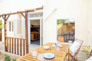 Ein Holztisch mit einem blauen Teller, einem Glas und einer weißen Schüssel auf einer Terrasse.