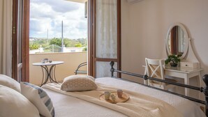 A bedroom with a bed, a bedside table, a chair, a small table with cups, and a view of the outside. - Villa Monica - Alghero (Alghero)