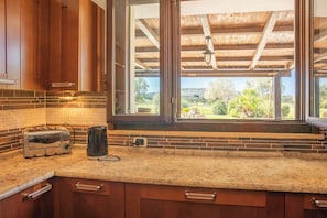 Eine Küche mit Toaster, Wasserkocher und Fensterblick auf einen Garten.