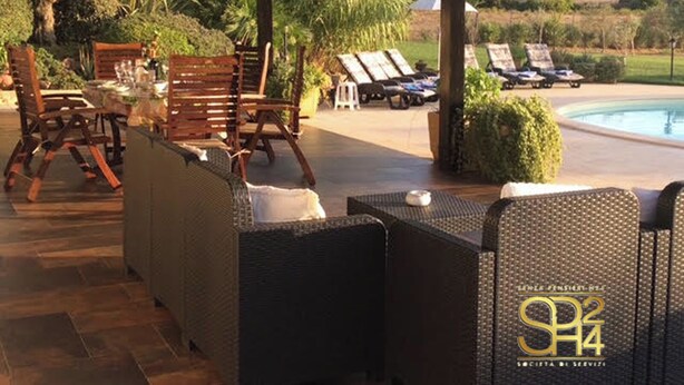 An outdoor patio with wicker furniture, a pool, and a view of the landscape. - Villa Monica - Alghero (Alghero)