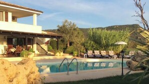 A pool area with lounge chairs, a building with a balcony, and a staircase leading to the upper floor. - Villa Monica - Alghero (Alghero)