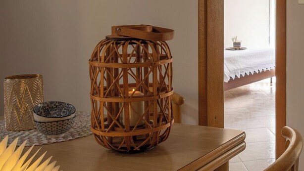 Une table en bois sur laquelle sont posés un chandelier en forme de panier tressé, un bol à motifs et un vase décoratif.