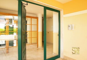 An open door leading to a room with a tiled floor, a wooden door frame, and a view of a balcony with a railing. - Red Coral Loft-Alghero (Alghero)