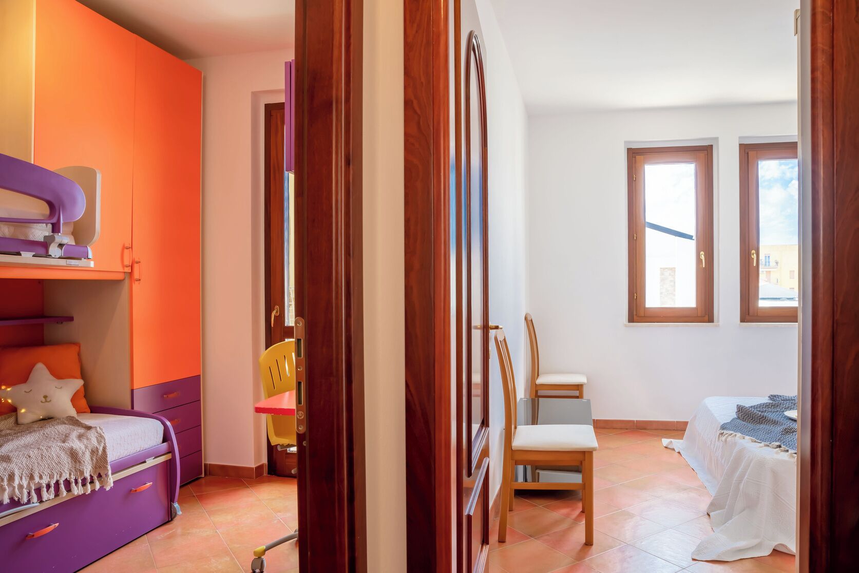 Une chambre à coucher avec un lit, une chaise, une petite table et une fenêtre.