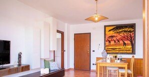 A living room with a TV, a wooden dining table, and a painting on the wall. - Red Coral Loft-Alghero (Alghero)