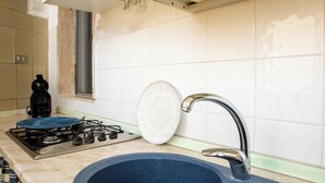 Una cocina con estufa a gas, un lavamanos y un ventanal.