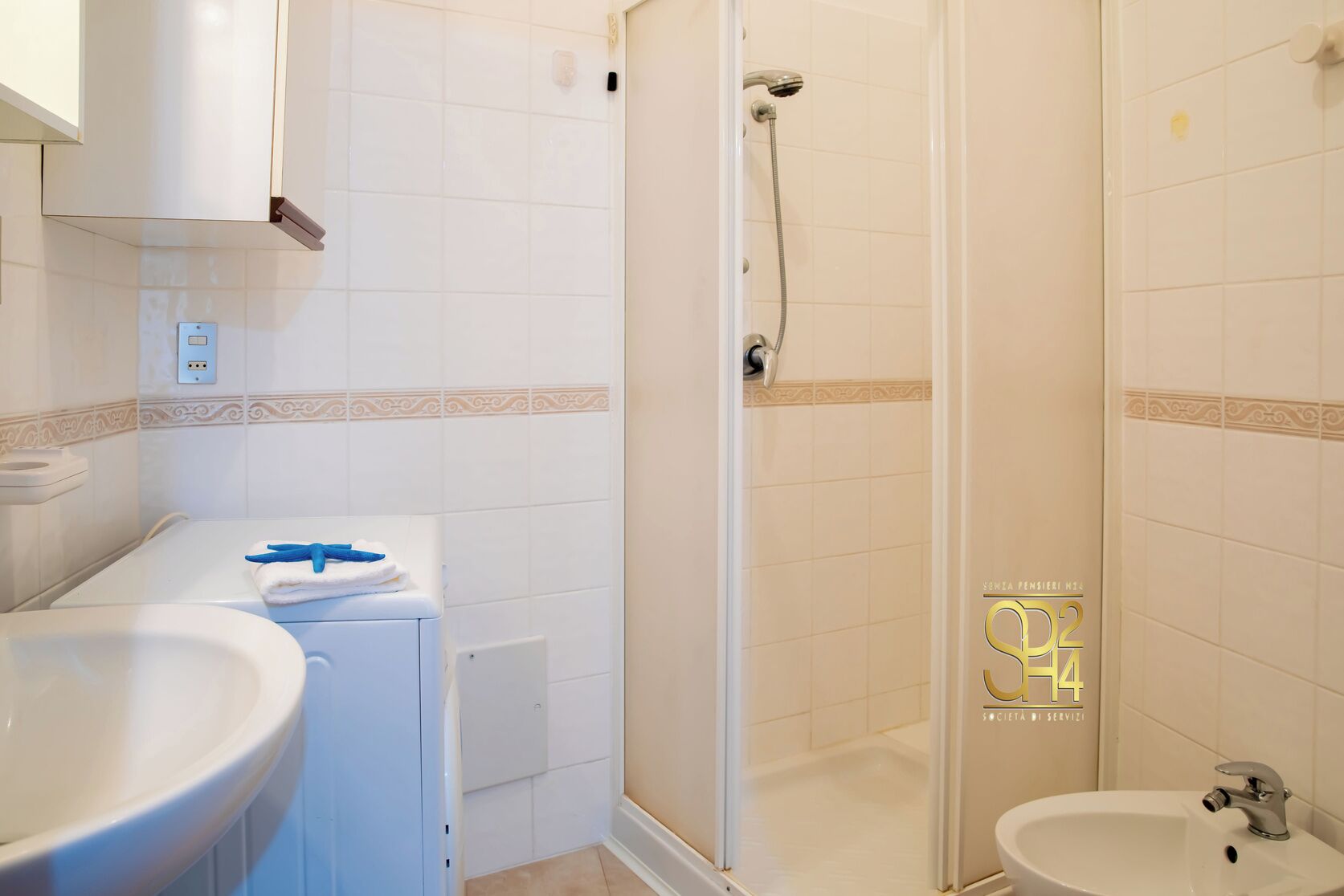 A bathroom with a shower, toilet, sink, and towel rack.