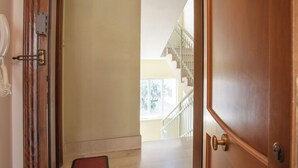 Un pasillo con una puerta de madera, un felpudo y una escalera que sube a un piso superior.
