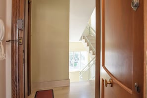 Ein Korridor mit einer Holztür, einer Fußmatte und einer Treppe, die zu einer oberen Etage führt.